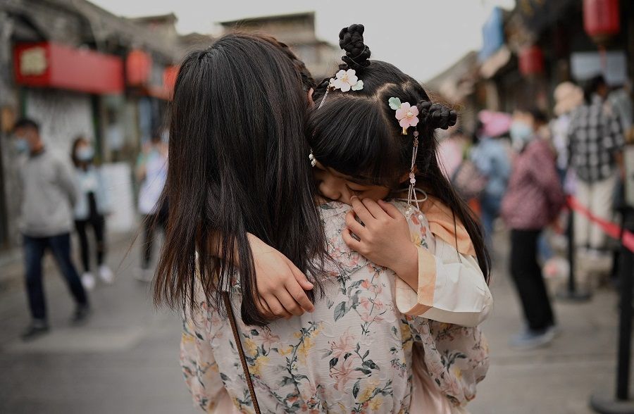 A mother carrying her child in an alley near Houhai Lake in Beijing, China on 4 May 2021. (Noel Celis/AFP)