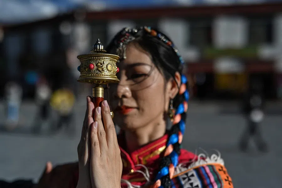 This photograph taken on 1 June 2021 during a government organised media tour shows a tourist posing for a photographer next to Jokhang Temple in the regional capital Lhasa, in China's Tibet Autonomous Region. (Hector Retamal/AFP)