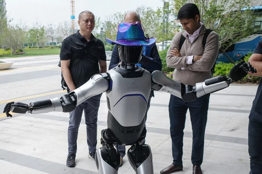 People interact with an Agibot RAISE A1 humanoid robot during a tour for foreign investors at the company's headquarters in Shanghai, China, on 20 April 2026.