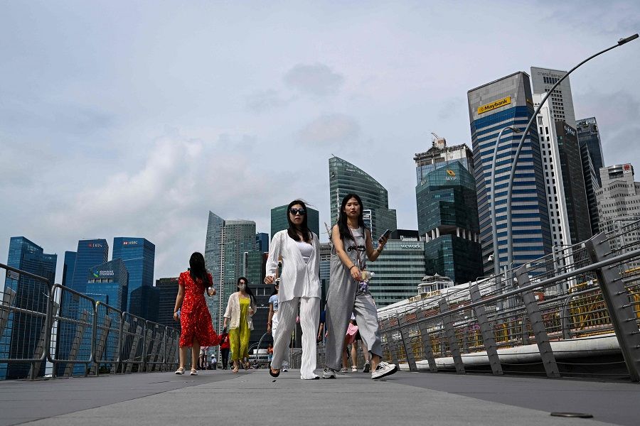 People walk at Marina Bay against the backdrop of commercial buildings in Singapore on 31 July 2023. (Mohd Rasfan/AFP)