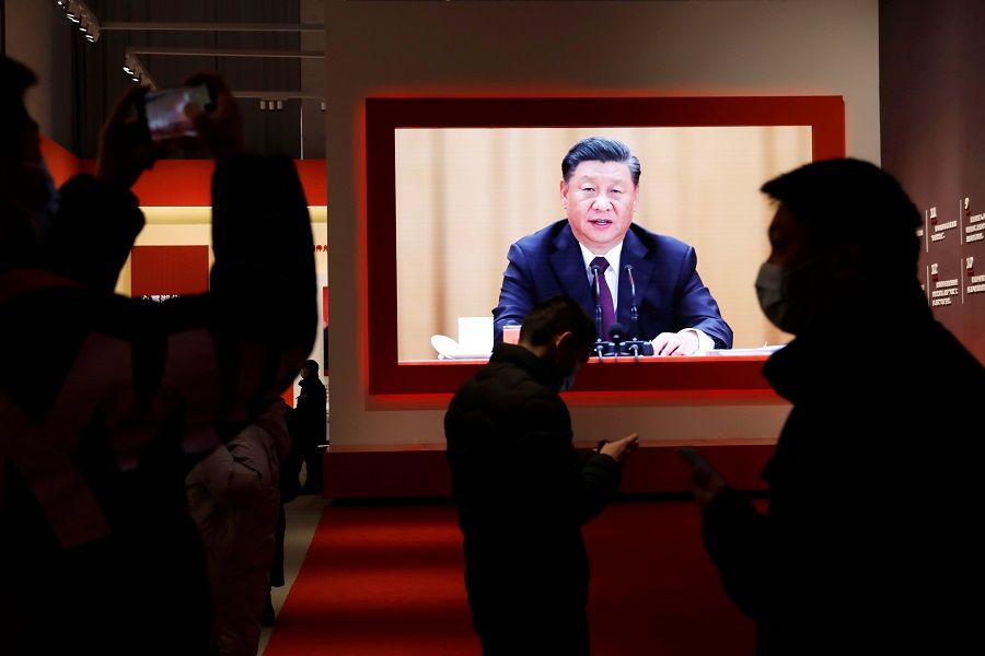Visitors are seen near a screen showing Chinese President Xi Jinping during an exhibition on the fight against the Covid-19 outbreak, at Wuhan Parlor Convention Center that previously served as a makeshift hospital for Covid-19 patients in Wuhan, Hubei province, China, 31 December 2020. (Tingshu Wang/Reuters)