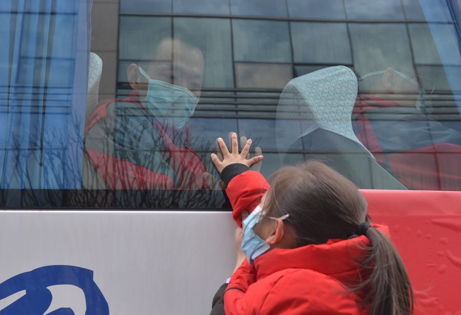 In this photo taken on 19 February 2020, a medical staff onboard a bus bids farewell to his daughter before leaving to fight the virus at the front line. (CNS)