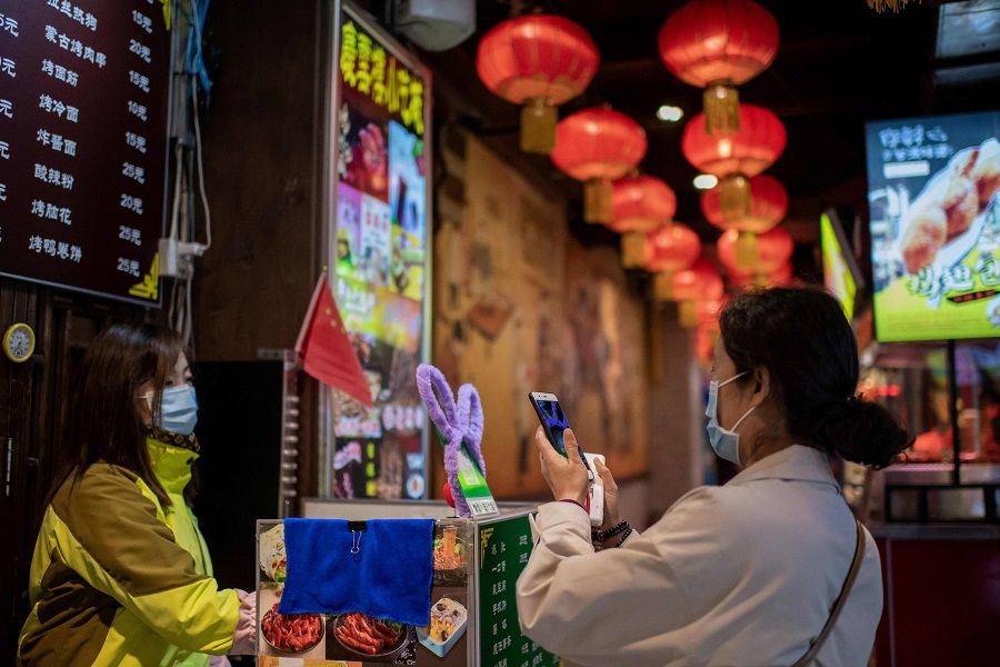 This picture taken on 28 October 2020 shows a customer (right) scanning a QR payment code (centre in green) to pay at a restaurant in Beijing, China. (Nicolas Asfouri/AFP)
