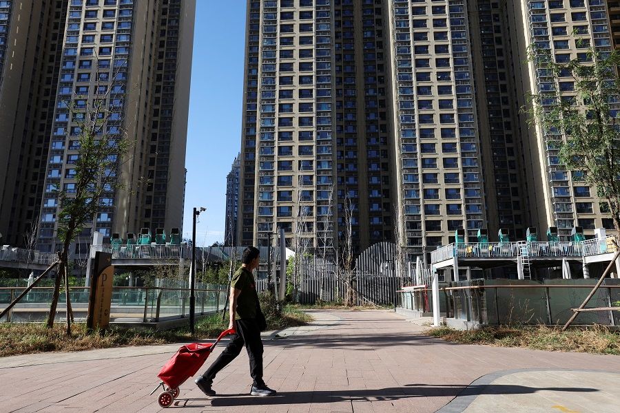A man pulls a cart past residential buildings at an Evergrande residential complex in Beijing, China, 27 September 2023. (Florence Lo/Reuters)