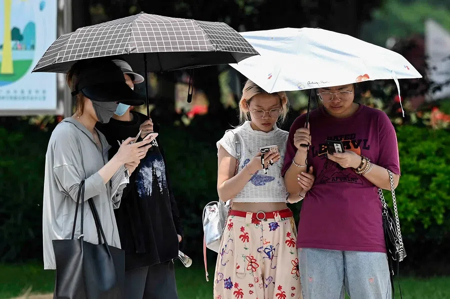 People use umbrellas to shelter from the sun amid hot weather in Guangzhou, Guangdong province, China, on 2 June 2023. (AFP)