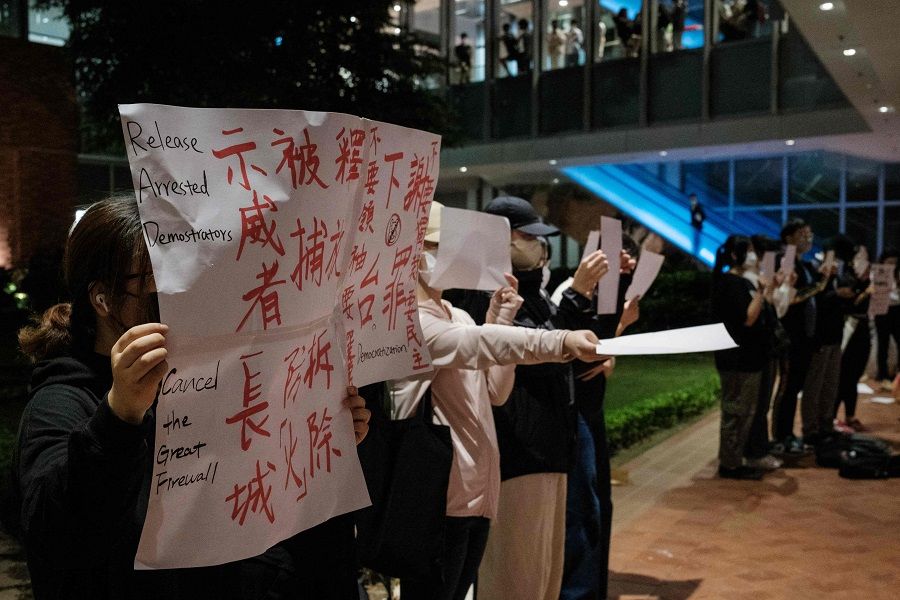 Protesters hold up a sign (left) and sheets of blank paper at the University of Hong Kong campus in solidarity with demonstrations in mainland China against strict Covid restrictions and demanding for greater freedoms, in Hong Kong, China, on 29 November 2022. (Yan Zhao/AFP)
