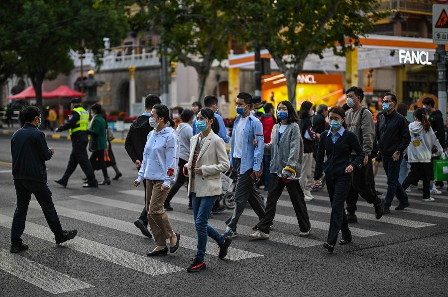 People cross a street in the Jing'an district in Shanghai, China, on 25 October 2022. (Hector Retamal/AFP)