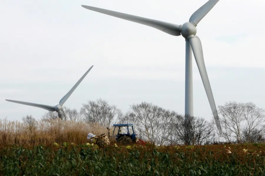 A farmer works near a wind turbine at the Electric Power Development Co., Ltd's Nunobiki Plateau Wind Farm in Koriyama, north of Tokyo, 8 November 2007. (Toru Hanai/Reuters)