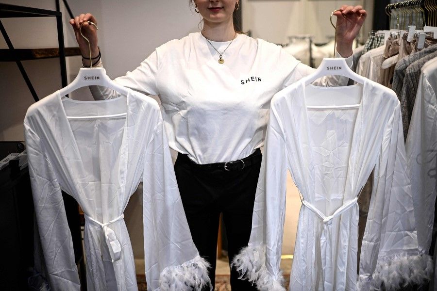 An employee shows clothes on sale at a Chinese fashion brand Shein pop-up store in Paris on 4 May 2023. (Christophe Archambault/AFP)