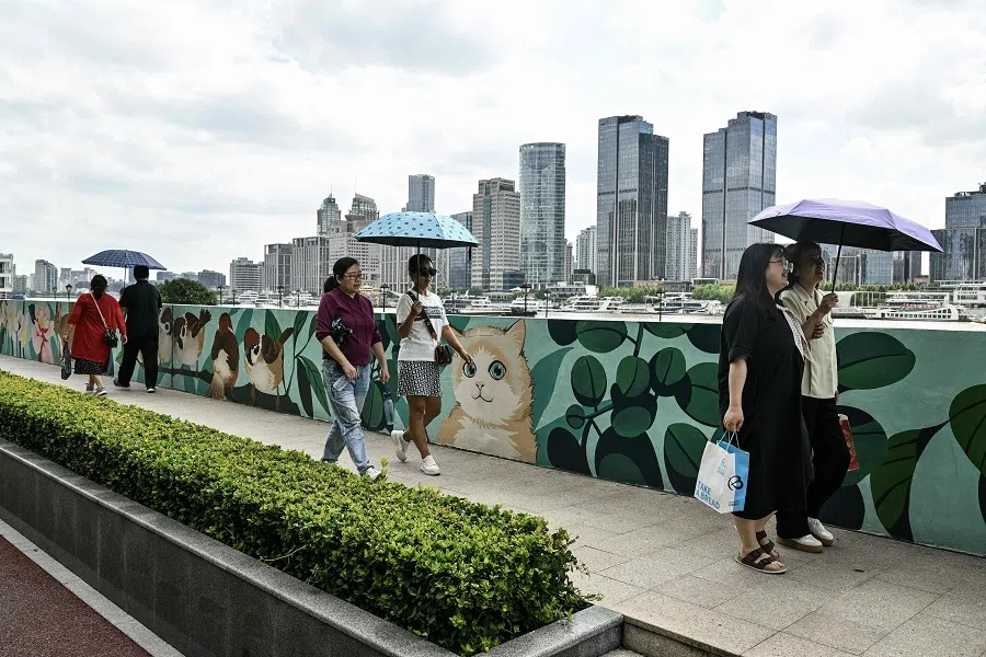 People walk along the bank of the Huangpu River at the financial district of Lujiazui in Shanghai on 23 September 2024. (Hector Retamal/AFP)