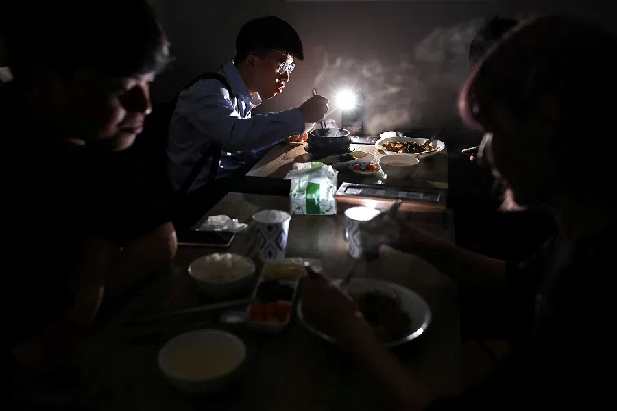 People eat using the light from their phone while experiencing a blackout due to a power outage in Taipei, Taiwan on 13 May 2021. (Ann Wang/Reuters)