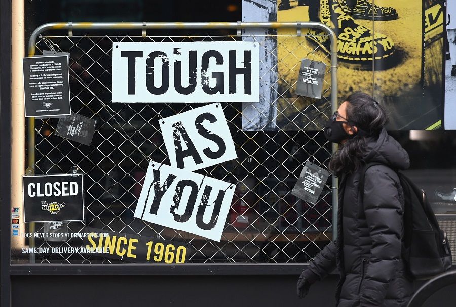 A person with a face mask walks by a Dr. Martens store on 25 March 2020 in New York City. (Angela Weiss/AFP)