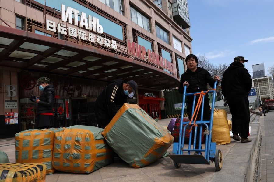 Men move bags of goods for export in front of a trading centre that houses shops and offices with Russian goods and services, in Beijing, China, 1 April 2022. (Tingshu Wang/Reuters)