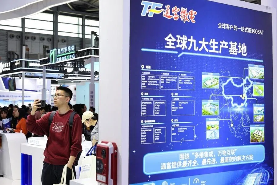 A visitor takes a photo at the Tongfu Microelectronics booth during SEMICON China, a trade fair for semiconductor technology, in Shanghai, China, on 25 March 2026.