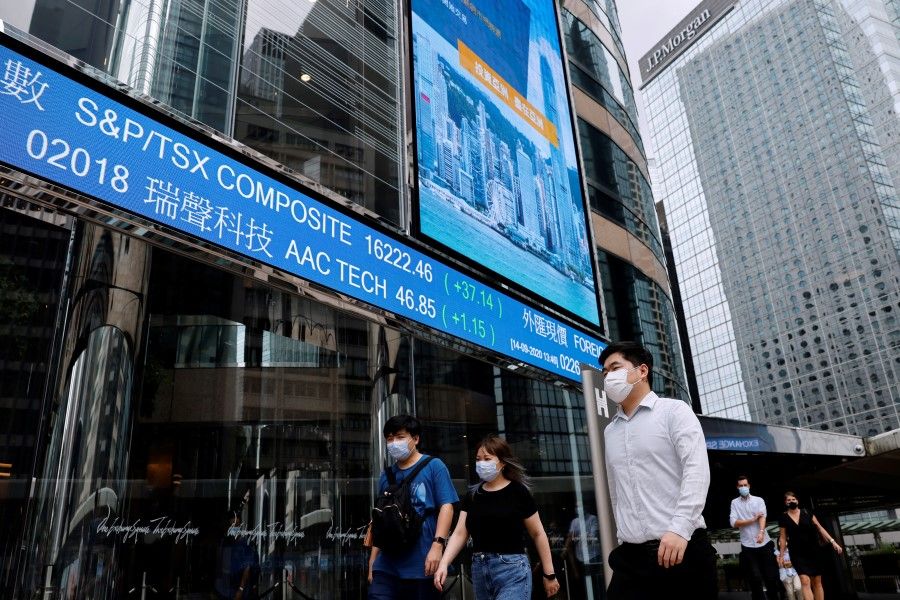 People wearing protective masks walk past screens outside the Hong Kong Exchanges, following the coronavirus disease (COVID-19) outbreak, at the financial Central district in Hong Kong, 14 September 2020. (Tyrone Siu/REUTERS)