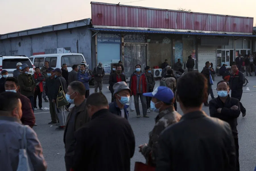 People stand on a street where labourers and migrant workers usually gather for odd jobs, near the border with Hebei province, following the Covid-19 outbreak, in Beijing, China, 20 April 2022. (Tingshu Wang/Reuters)