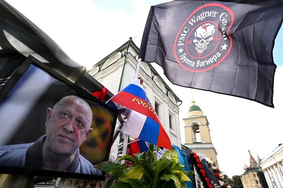 A flag bearing the logo of private mercenary group Wagner flutters above a portrait of the late head of Wagner paramilitary group, Yevgeny Prigozhin, at a makeshift memorial in Moscow, Russia, on 27 August 2023. (Natalia Kolesnikova/AFP)