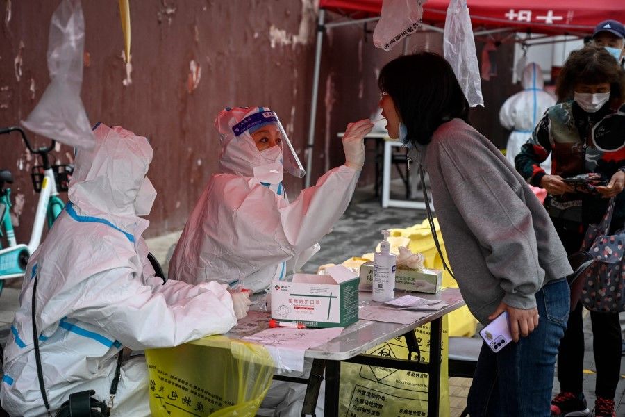 A health worker takes a swab sample from a woman to be tested for Covid-19 coronavirus at a makeshift testing site in Beijing on 27 April 2022. (Jade Gao/AFP)