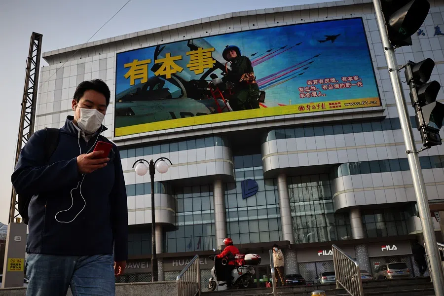 An advertisement of the People's Liberation Army overlooks a street scene in Beijing, China, 16 November 2021. (Thomas Peter/Reuters)