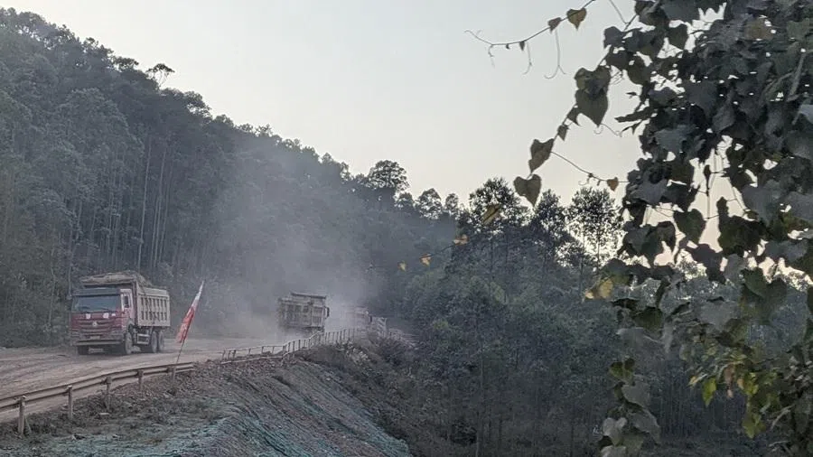 Large trucks transporting building materials for the construction of the Pinglu Canal kick up clouds of dust, coating vegetation outside Shiqiao village. (SPH Media)