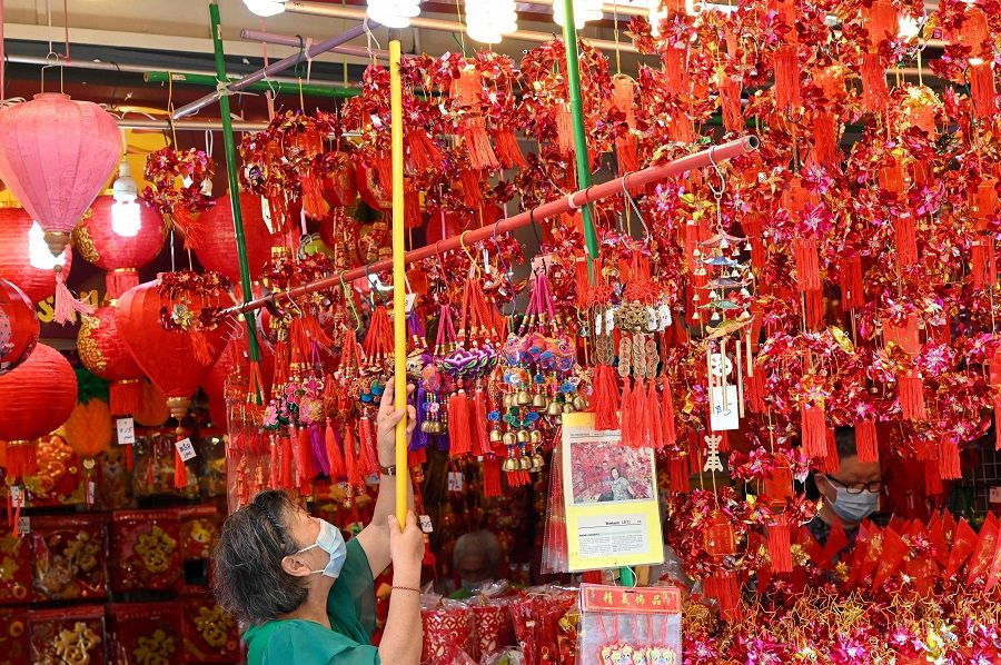 A vendor hangs decorative ornaments for sale for the upcoming Lunar New Year of the Tiger in the Chinatown district in Singapore on 10 January 2022. (Roslan Rahman/AFP)