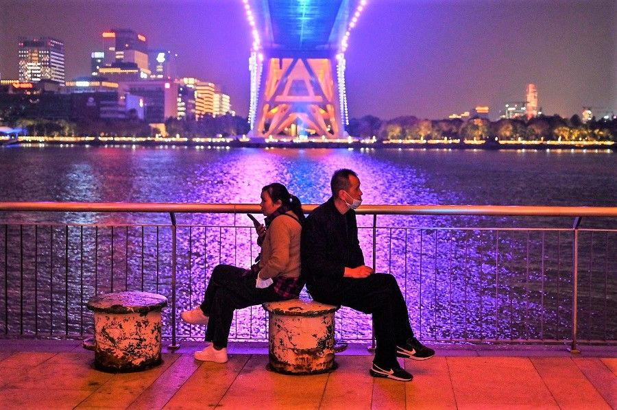 A couple sits in a promenade along the Huangpu River under Lupu Bridge in Shanghai, China, on 9 November 2022. (Hector Retamal/AFP)