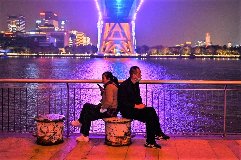 A couple sits in a promenade along the Huangpu River under Lupu Bridge in Shanghai, China, on 9 November 2022. (Hector Retamal/AFP)