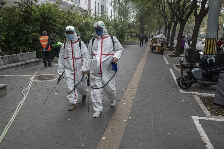 Workers with disinfecting sprays walk through a street in Beijing, China, on 5 November 2021. (Gilles Sabrie/Bloomberg)