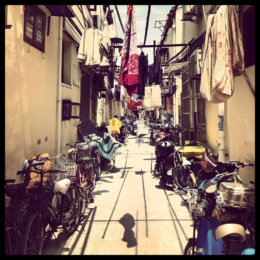 Parked bicycles and laundry share a lane on a sunny day in Huangpu district.