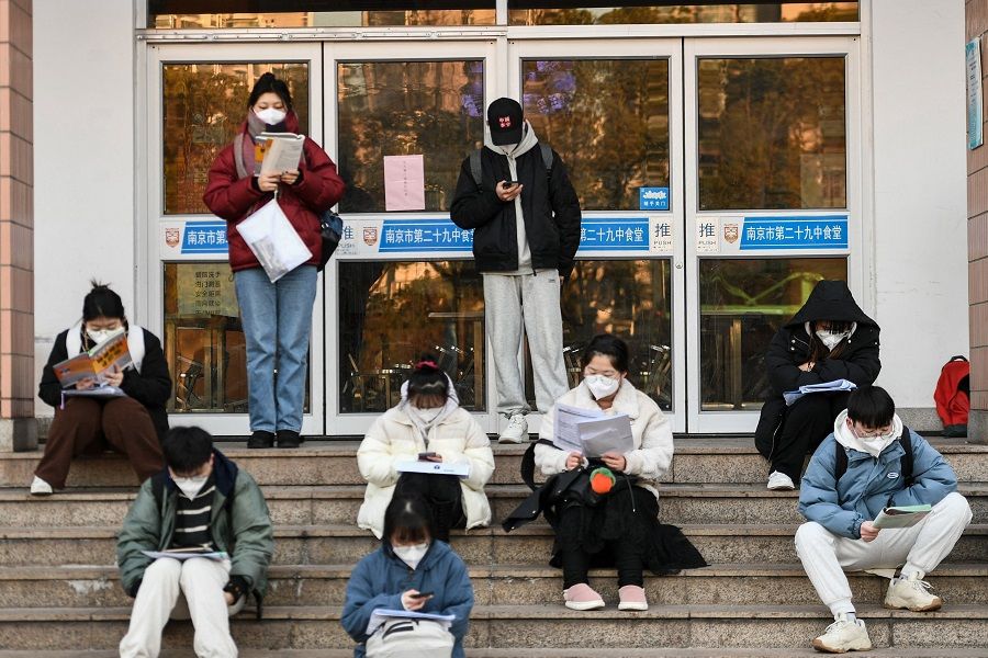 This photo taken on 24 December 2022 shows students reading books as they arrive for the National Postgraduate Entrance Exam in Nanjing, Jiangsu province, China. (AFP)