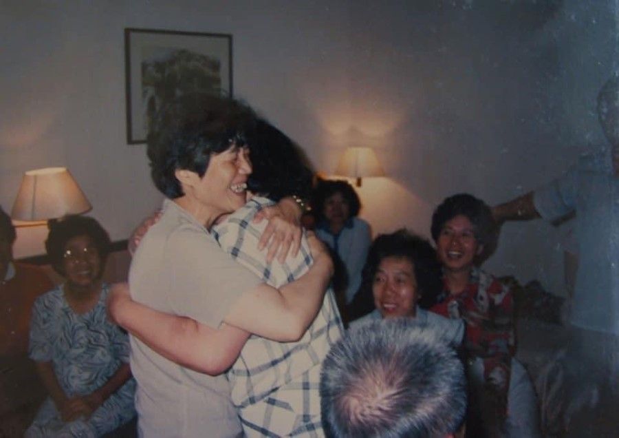 Lin Liyun (standing, left) and her relatives from Qingshui, Taichung, embrace as they gather in a hotel room in 1989.