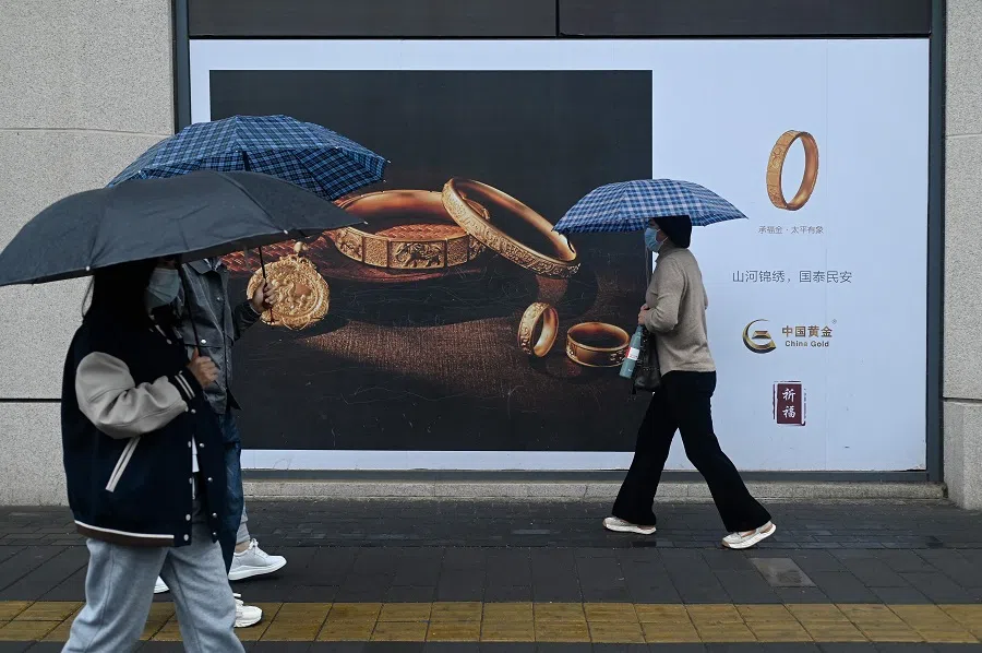People walk past a gold advertisement in Beijing, China, on 10 April 2024.