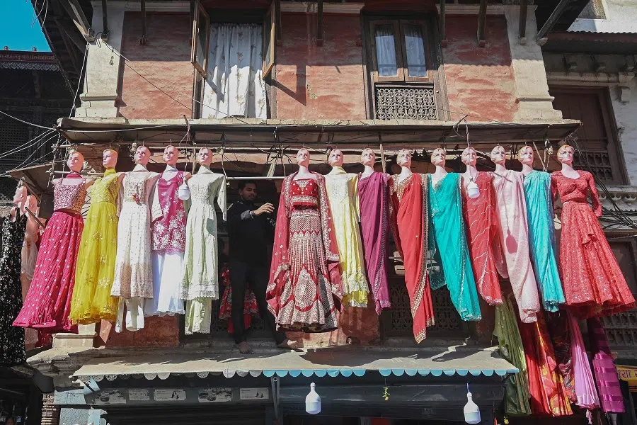 A shopkeeper arranges mannequins for display above his shop in Kathmandu on 5 December 2024. (Prakash Mathema/AFP)