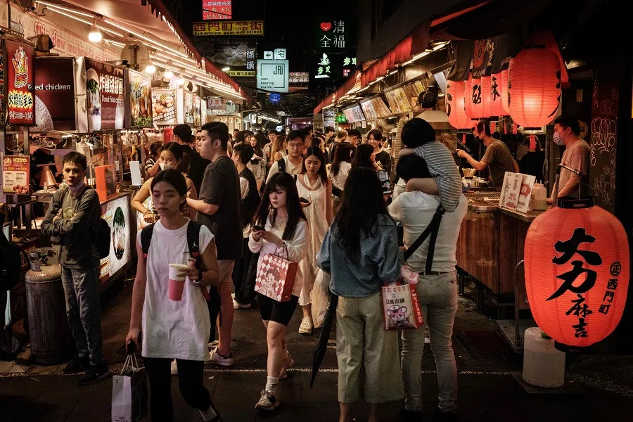 People walk past food vendors along a street in Taipei on 26 May 2024.  (Yasuyoshi Chiba/AFP)
