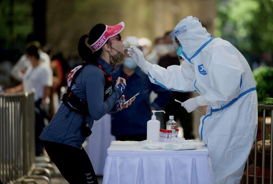 A health worker gets a swab test sample from a woman to be tested for Covid-19 at a swab collection site in Beijing, China, on 15 May 2022. (Noel Celis/AFP)