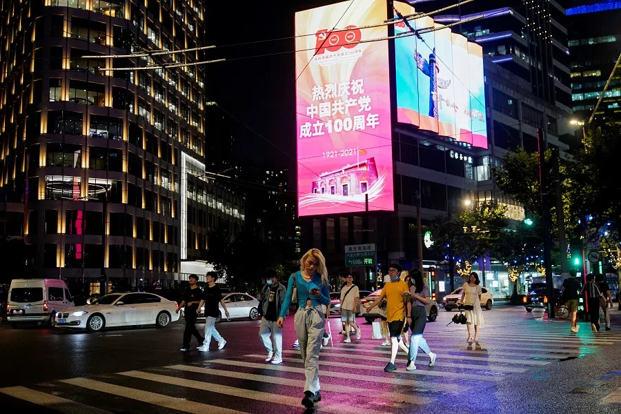 People walk on a street in front of a screen marking the 100th founding anniversary of the Communist Party of China, in Shanghai, China, 15 June 2021. (Aly Song/Reuters)