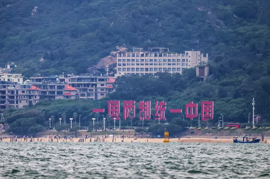 A giant sign reading "One Country, Two Systems; Reunify China" is seen at a beach in Xiamen, Fujian province, in Kinmen on 28 October 2025. (I-Hwa Cheng/AFP)