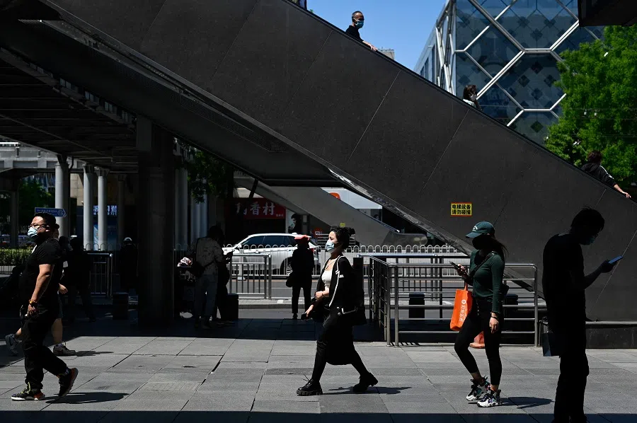 People walk along a street at a business district in Beijing, China, on 16 May 2022. (Wang Zhao/AFP)