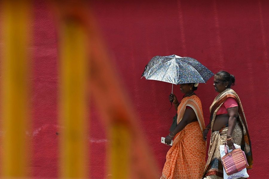 A woman shelters from the sun with an umbrella during a hot summer day in Chennai, India, on 16 May 2023. (R. Satish Babu/AFP)