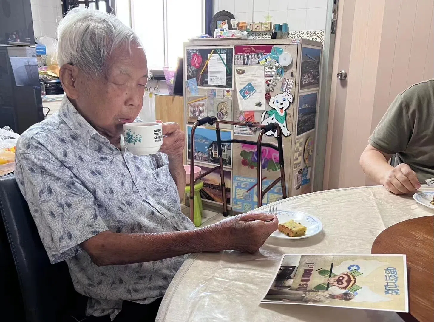 Ho enjoying a cup of coffee as he looks at a colourised photo of himself when he was young. 