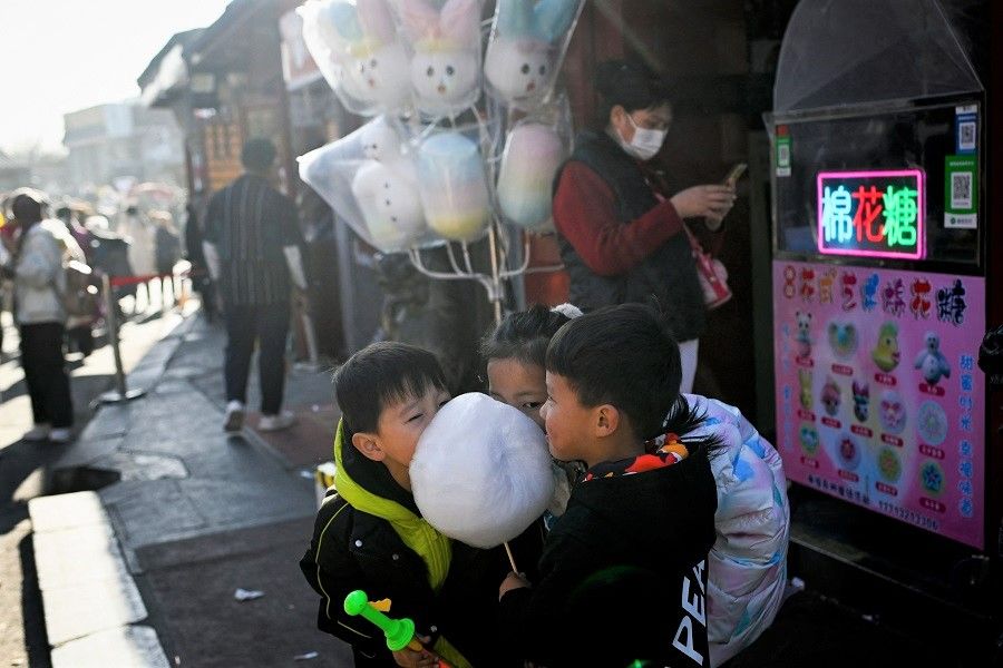 Children share candy floss as they visit a hutong (alley) in Beijing, China, on 31 January 2023. (Wang Zhao/AFP)