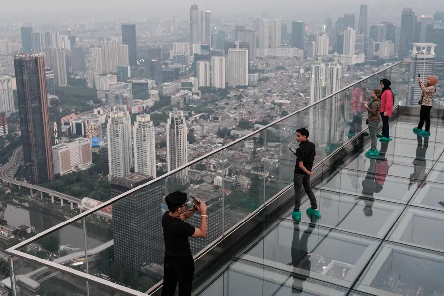 People stand on a transparent-floor deck of an observatory claimed to be Indonesia's highest, at the Thamrin Nine building in Jakarta on 24 July 2025. (Yasuyoshi Chiba/AFP)