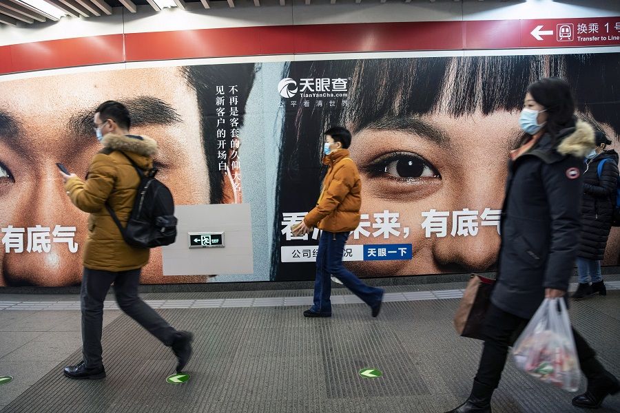 People wearing protective masks walk past an advertisement at a subway station in Beijing, China, on 3 March 2021. (Qilai Shen/Bloomberg)