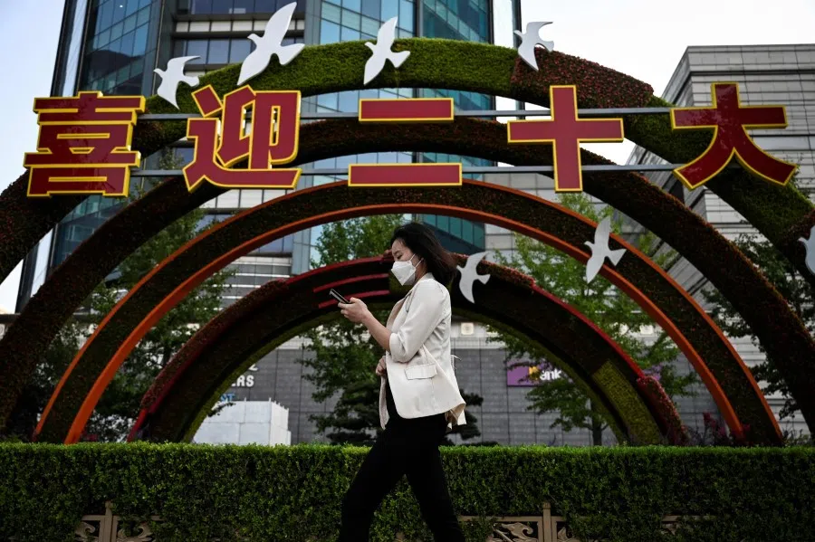 A woman walks past an installation to celebrate the 20th Party Congress, along a street in Beijing on 21 September 2022. (Jade Gao/AFP)