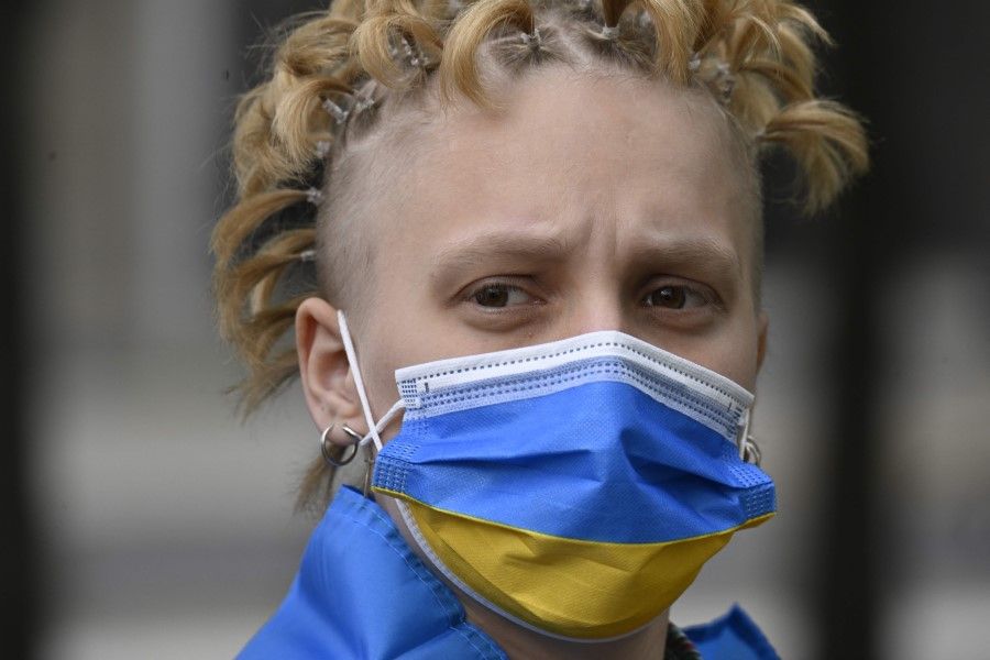 A demonstrator wearing a face mask in the colours of the Ukraine flag attends a protest rally against the war in Ukraine at the German Chancellery in Berlin on 4 May 2022. (Tobias Schwarz/AFP)
