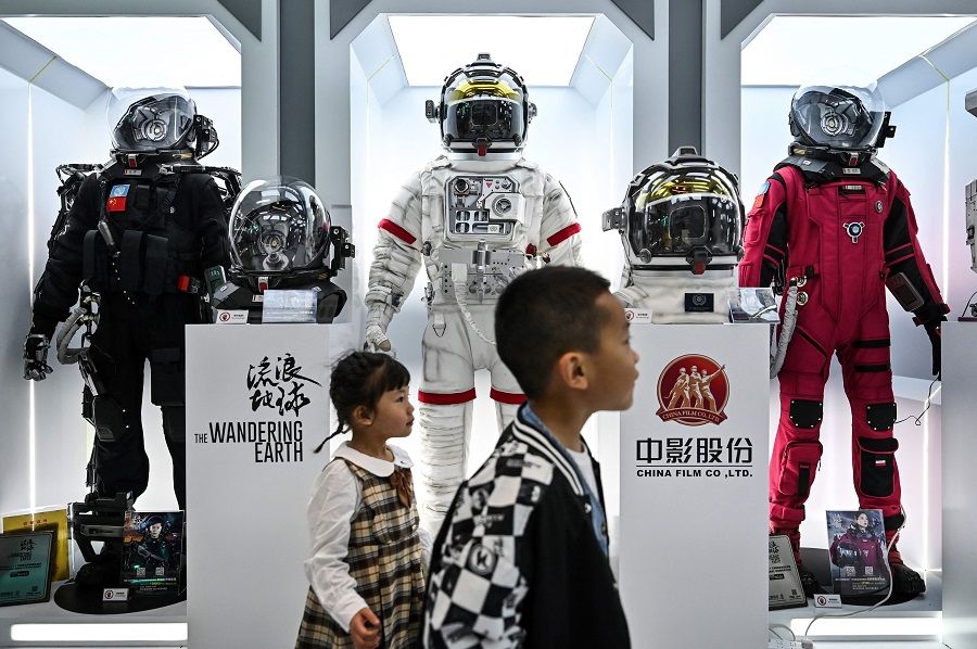 Children walk past space suits of the Chinese sci-fi movie The Wandering Earth on display at the 2023 World Science Fiction Convention in Chengdu, Sichuan province, China, on 20 October 2023. (Hector Retamal/AFP)