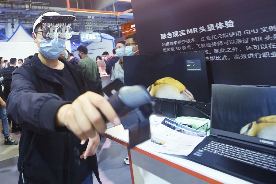 A visitor tries mixed reality glasses at the Apsara Conference, a cloud computing and artificial intelligence (AI) conference, in Hangzhou, Zhejiang province, China, on 19 October 2021. (STR/AFP)