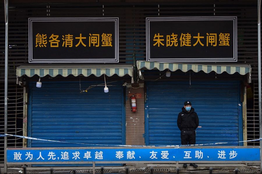 In this file photo taken on 24 January 2020, a security guard stands outside the Huanan Seafood Wholesale Market where the coronavirus was detected in Wuhan, Hubei province, China. (Hector Retamal/AFP)
