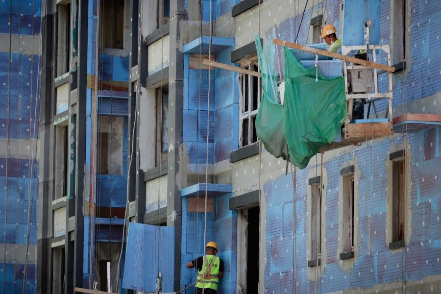 Men work at a construction site of apartment buildings in Beijing, China, 15 July 2022. (Thomas Peter/Reuters)