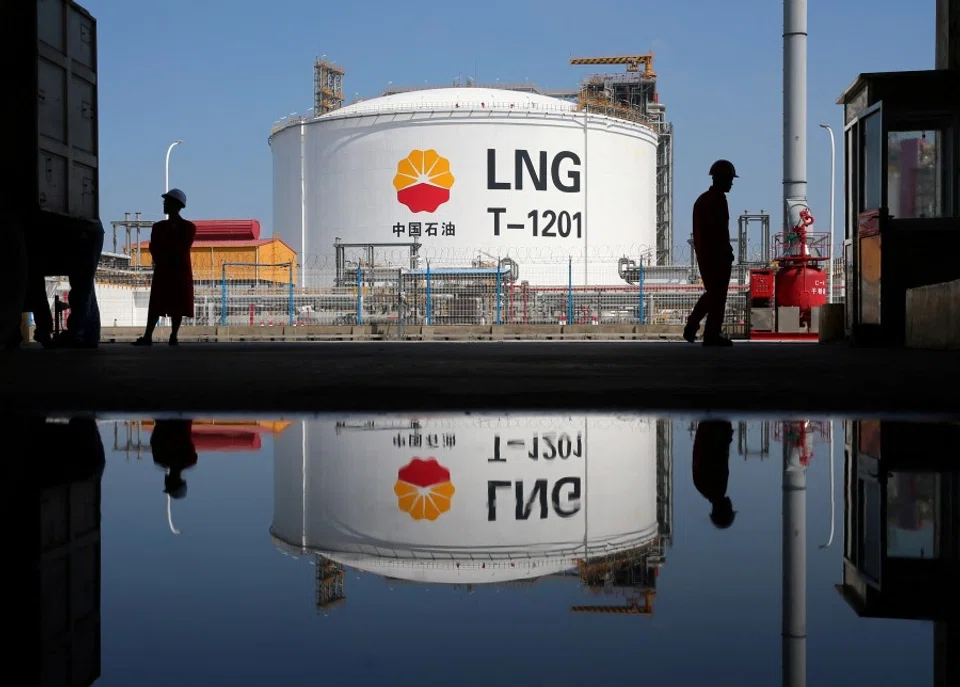 A liquified natural gas (LNG) storage tank and workers are reflected in a puddle at PetroChina's receiving terminal at Rudong port in Nantong, Jiangsu province, China, 4 September 2018. (Stringer/Reuters)